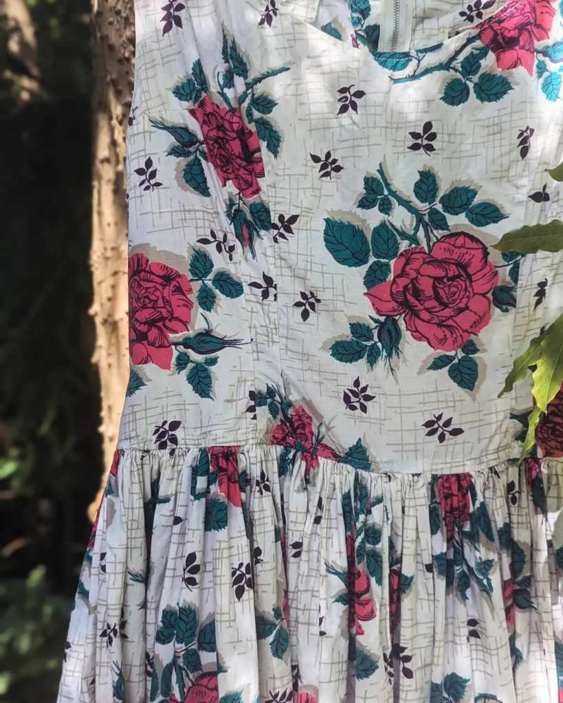 A close-up of the print: pink roses and clusters of leaves on an abstract, atomic pattern.