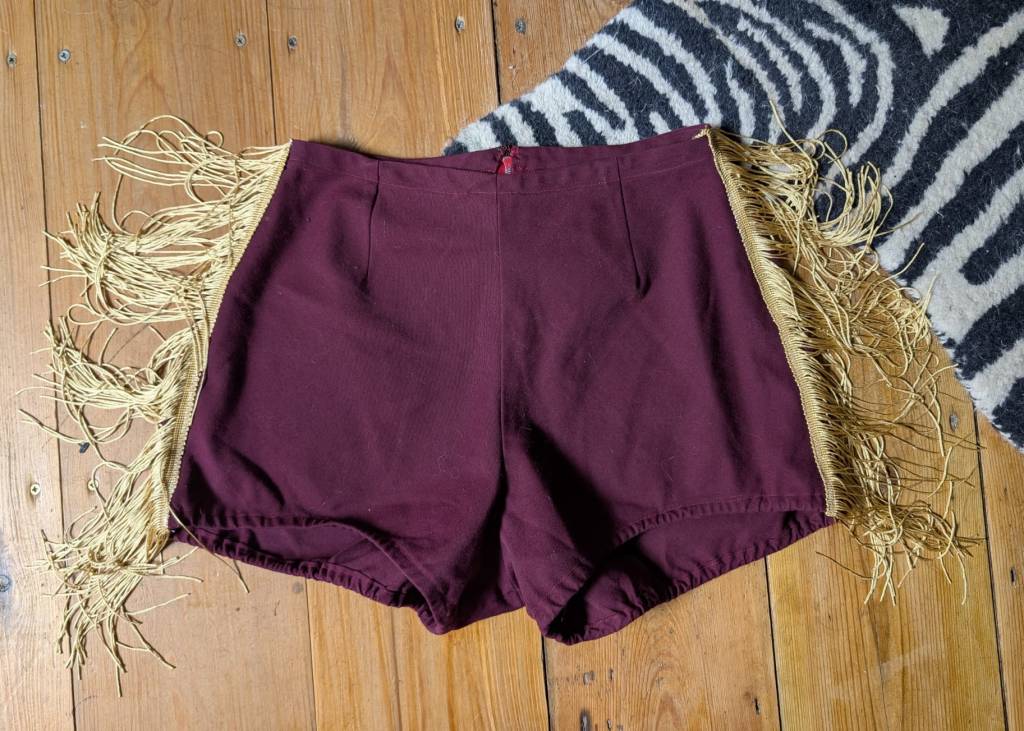 1960s burgundy cheerleader hot pants with gold fringe trim down the sides
