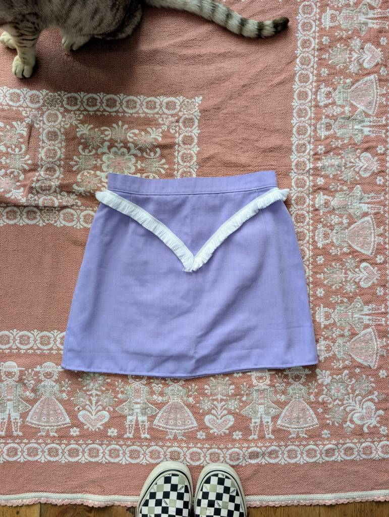 A lilac mini skirt with white fringe in a V