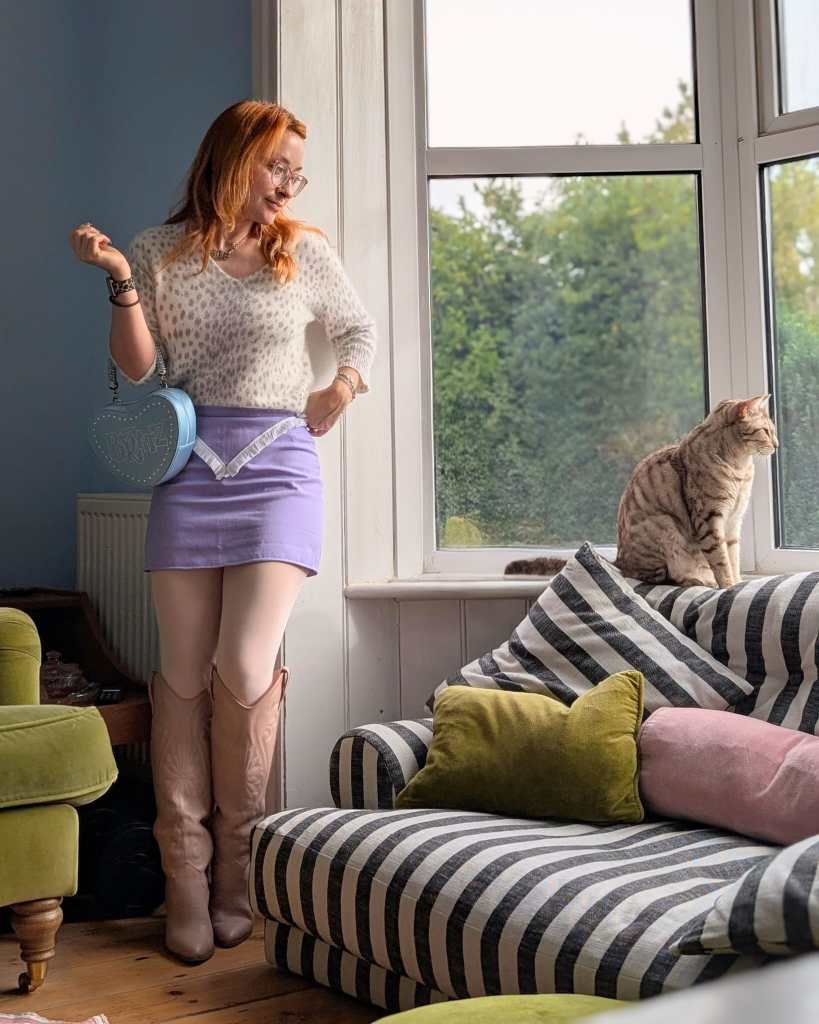 Honor wearing the lilac skirt, pink cowboy boots, a snow leopard print mohair sweater and a pale blue heart-shaped Bratz bag