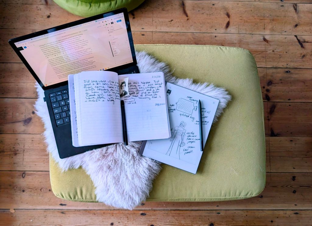 A green velvet footstool with a notebook, a laptop and a tablet on it